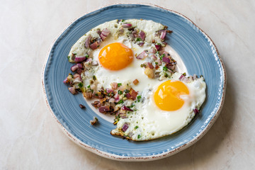 Sunny Side Up Fried Eggs with Red Onions and Chives for Breakfast in Plate.