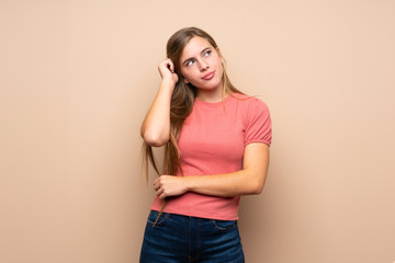 Teenager blonde girl over isolated background having doubts and with confuse face expression