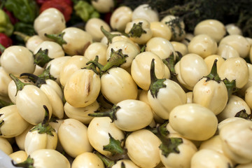 pile of mini eggplants in a box for sale at a market.