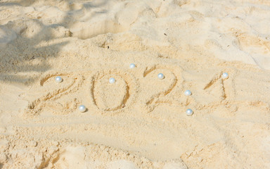 Happy New Year 2021 text  in the sand with Christmas ball, travel and vacation concept