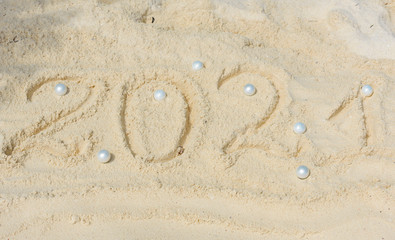 Happy New Year 2021 text  in the sand with Christmas ball, travel and vacation concept