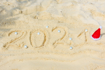 Happy New Year 2021 text  in the sand with Christmas ball, travel and vacation concept
