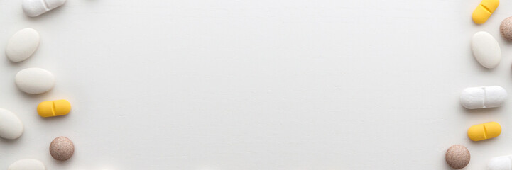 Tablets on a white wooden table. Pharmacy and pharmacology. Top view backgound. Tablet frame. Copy space. Panorama