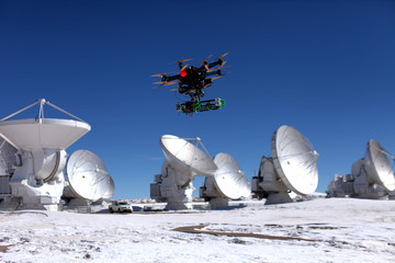 Große ferngesteuerte drohne fliegt über emfangsantennen eines radioteleskops
