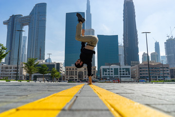 Acrobat keep balance one the hands with blurred Dubai cityscape. Concept of modern, business and unlimited possibility