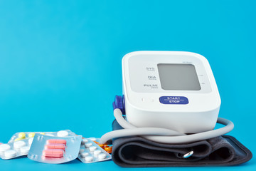 Digital blood pressure monitor and medical pills on a blue background. Healthcare and medicine...