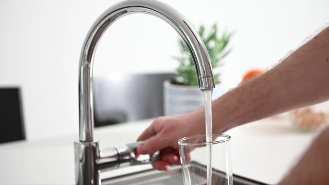 Fresh water running from a tap in a kitchen, there is a fruit bowl in the background, stock footage by Brian Holm Nielsen