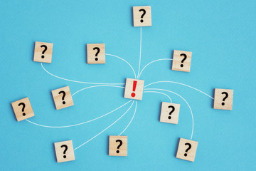 Leadership and solution task concept. Wooden blocks with question marks connected to exclamation mark on a blue background