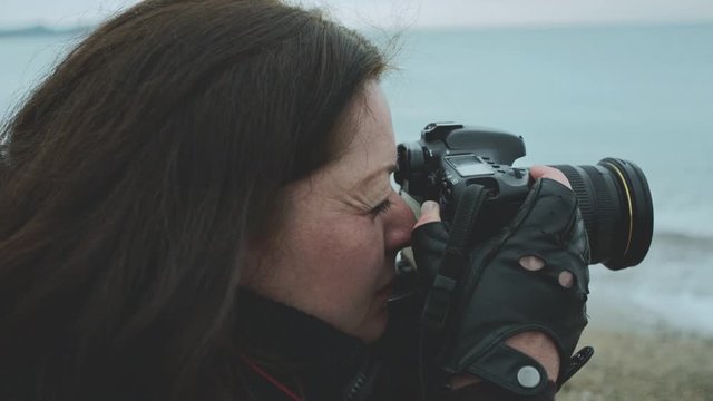 Woman photographer takes photo on the beach in autumn