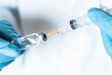 Doctor, nurse or scientist hand in blue nitrile gloves holding flu, measles, coronavirus vaccine...