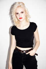 young sexy blonde girl in a black t-shirt and black jeans on a white background, studio fashion...