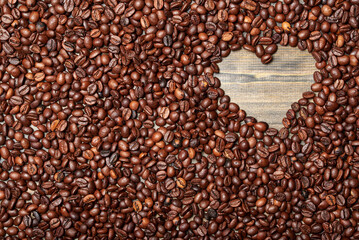 Roasted coffee beans on a wooden table. Heart shaped neckline. View from above. ?opy space