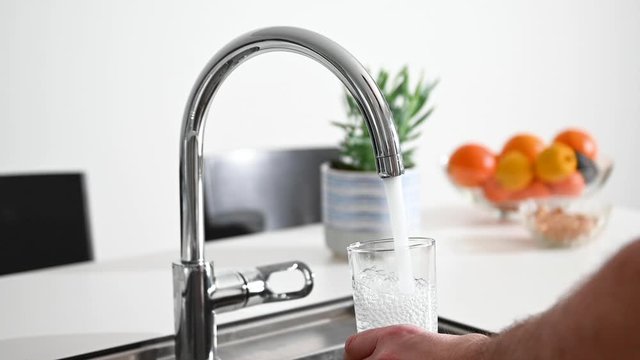 Fresh water running from a tap in a kitchen, there is a fruit bowl in the background, stock footage by Brian Holm Nielsen