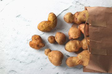 Organic ugly potatoes in a paper bag on a marble background, organic vegetables concept, Zero waste...