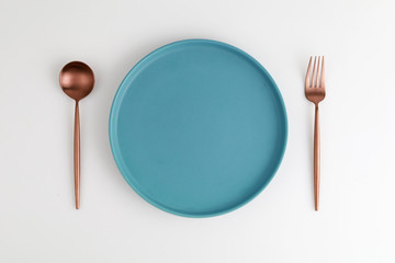 Empty blue plate with spoon and fork on white background