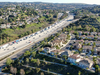 Fototapeta na wymiar Aerial view of highway with traffic surrounded by houses in Diamond Bar City. Intersection city transport road with vehicle movement. Eastern Los Angeles, California, USA.