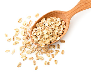 Oatmeal spilled from a wooden spoon close-up on a white. The view from the top