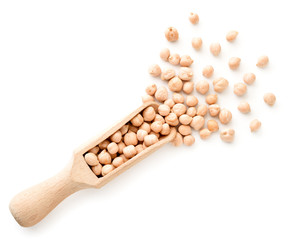 Chickpeas spilled from a wooden scoop on a white background. The view from top
