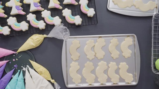Step by step. Flat lay. Decorating unicorn theme sugar cookies with royal icing on baking sheet.