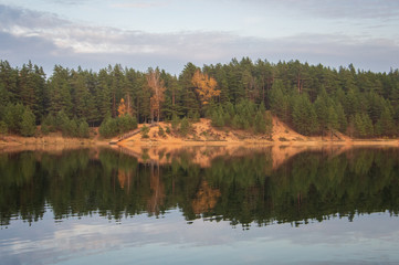 View to the coniferous forest in autumn in Ogre Zilie Kalni (Blue Hill) Nature Park over Dubkalni Reservoir with the beautiful reflections in the water