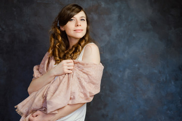 Feminine sensual girl posing on a black background. Portrait of a young European woman with curly brown hair. Femininity and natural beauty.