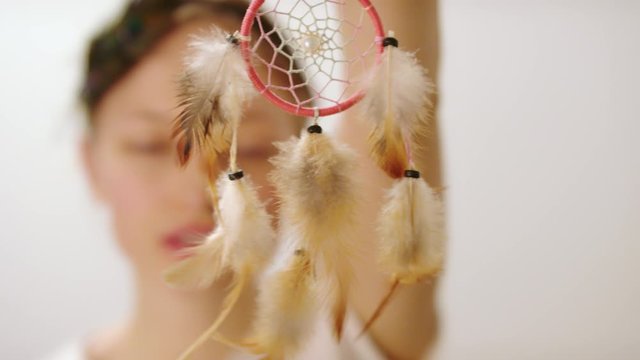 A woman showing a dreamcatcher with feathers hanging decor - Close-up shot