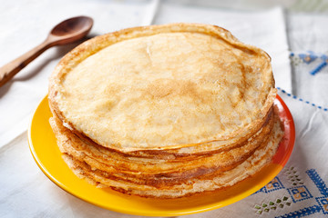 Stack of pancakes. Thin pancakes in a plate and a wooden spoon. Traditional rustic food.