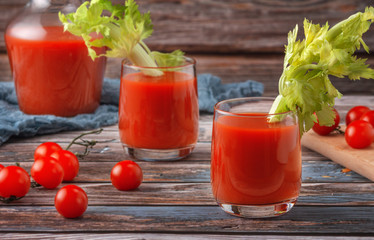 Two glasses of tomato juice on a wooden table, on a wood background, fresh drink