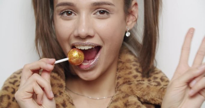 female model wearing leopard fur coat licking candy
