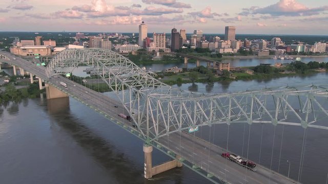 Aerial flying over traffic on the Hernando de Soto Bridge that crosses the Mississippi River at sunset. In the background is downtown Memphis, Tennessee, USA