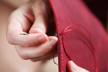 Conceptual profession of a Tanner. The woman's hands closed around the needle and thread.