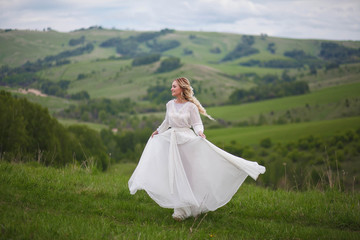 the bride walks in the field against the backdrop of the mountain