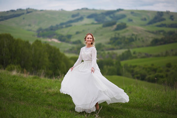 the bride walks in the field against the backdrop of the mountain