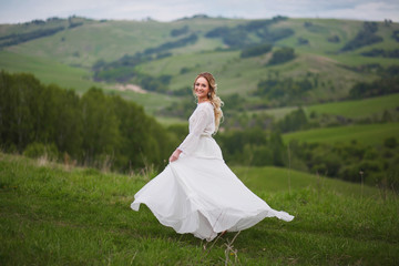 the bride walks in the field against the backdrop of the mountain