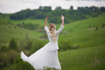 the bride walks in the field against the backdrop of the mountain