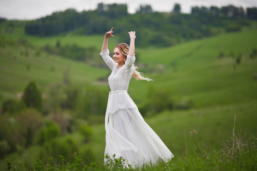 the bride walks in the field against the backdrop of the mountain