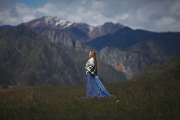a girl walks in a field on a background of snow-capped mountains than the Chemal district