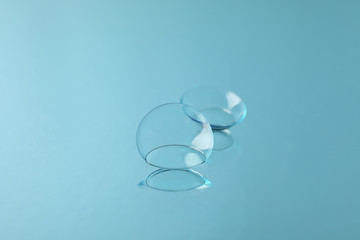 Contact lenses on blue mirror surface, close up