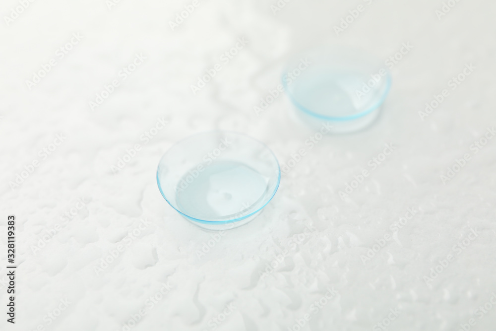 Sticker contact lenses on white background with water, close up