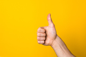 male big thumb up against yellow background with copy space. hand with like sign