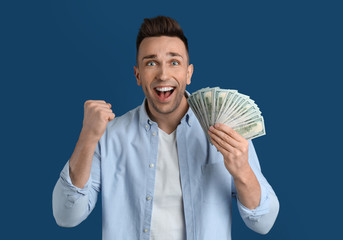 Emotional man with cash money on blue background