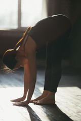 girl in black sportswear standing hands reach the floor. Yoga training.