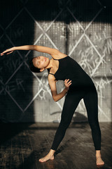 Fototapeta premium Girl is doing stretching exercise. Yoga class in black sportswear.
