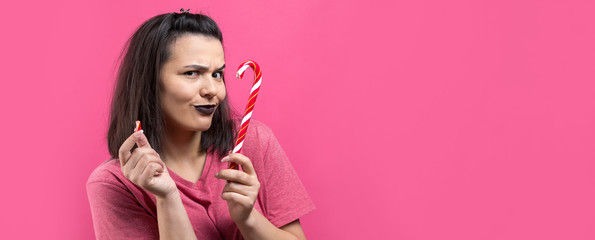 Portrait of lovely sweet beautiful cheerful woman with straight brown hair trying to bite red candy cane christmas.