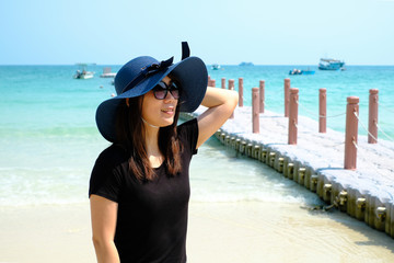 Portrait of Asian woman wearing blue hat smiling on the beach of Samed Island, Thailand.