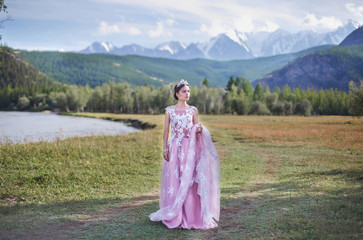Fototapeta premium Queen. The girl in the image of a queen on a background of mountains