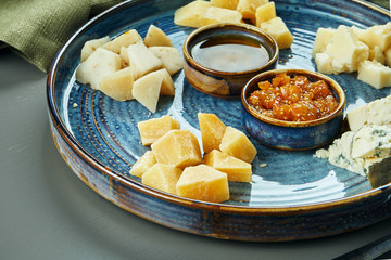 Antipasto - a cheese plate. Different, homemade cheeses on a ceramic plate - brie, camembert, Dutch with honey and nuts. Wine appetizer. Close up, selective focus