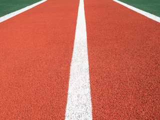 Perspective view of red running track with white lines. Sports background