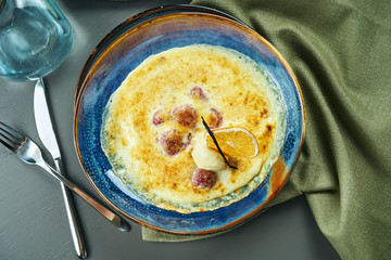 Berry gratin with ice cream in a blue bowl on wooden background. Tasty and sweet french baked dessert. Top view, flat lay, central composition