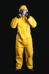 Man wearing chemical protective suit on black background. Virus research